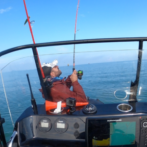 Un pêcheur est sur le zodiac, un poisson vient de mordre à son hameçon, il tire sur sa canne à pêche pour avoir le poisson. Le bateau se trouve sur les côtes de Saint-Michel-Chef-Chef.